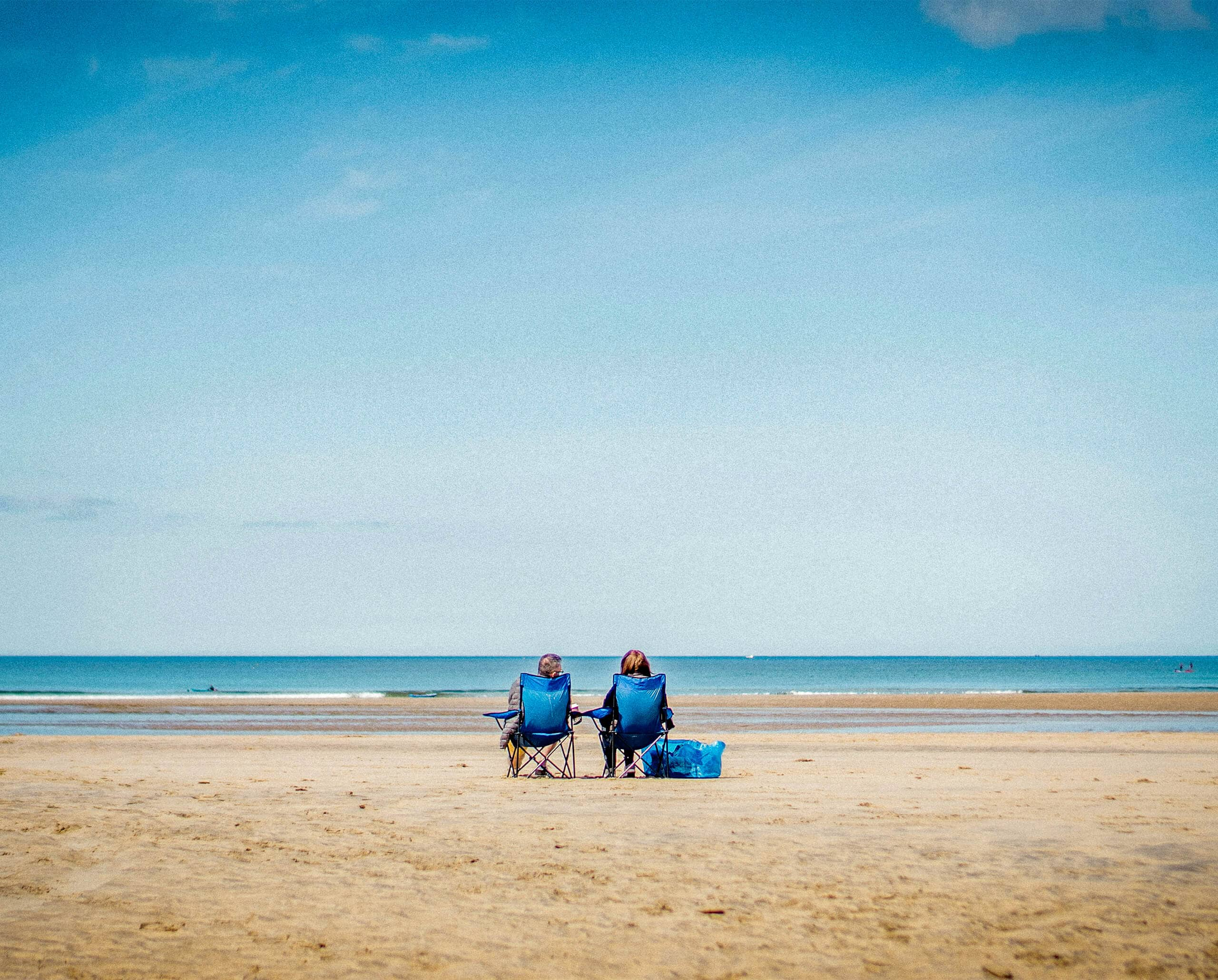 People resting on beach in blue folding chairs